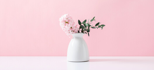 Pink hyacinth, eucalyptus on pink wall background. Spring flower hyacinth in vase on pink background. banner