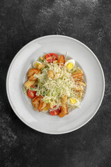 Caesar salad with shrimps, on a dark background.