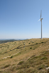 A wind farm fan on a hillside casts its shadow in the shape of a crucifix