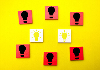 Colored cubes with lit and non-lit bulb icons isolated on yellow background.
