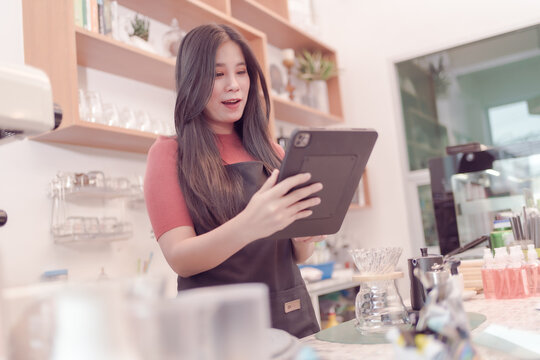 Asian woman who owns this coffee shop. checking Daily coffee shop sales data on his tablet and it seems Sales will be especially good. which made the owner very happy