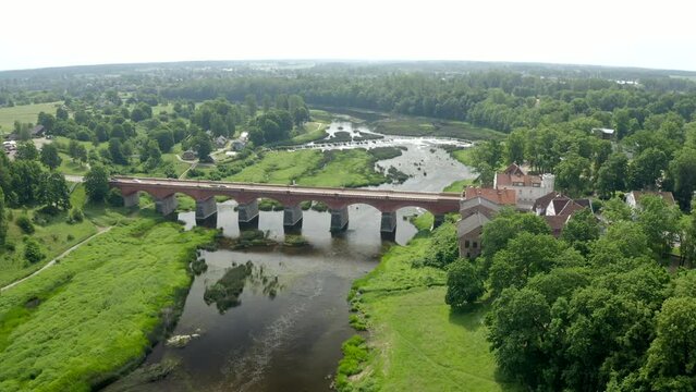 Drone flight in Northern Europe - Latvia - Kuldiga. Flight across wides waterfall in northern Europe fiying upstream on river Venta - revealing green vegetation of river. Mid summer. People swimming