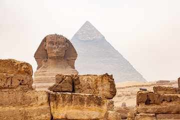 View of Statue of The Great Sphinx of Giza in The Giza Plateau and The Great Pyramid of Giza in the background. - obrazy, fototapety, plakaty