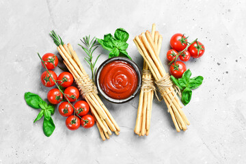 Grissini. Bread sticks with ketchup, basil and spices on a gray stone background. Food. Top view. Free space for text.