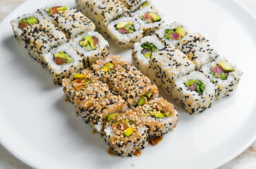 Traditional sushi rolls and maki with sesame, avocado and fish. Japanese food. Top view. On a white background.