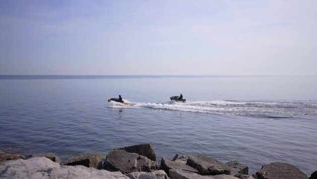 Jet skis in Lake Ontario, Canada. Jet ski on water personal watercraft fast boat sea doo driving in water in Toronto, Ontario, Canada near rocky stone shore beach