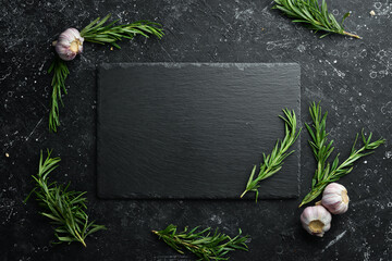 Table setting. Slate black stone plate with rosemary and garlic. Top view. Free copy space.