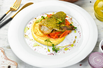 Roasted sea bass fillet with vegetables on a white plate. Top view. Rustic style.