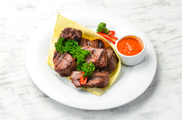 Juicy pork skewers with pita bread and sauce on a white plate. Top view.