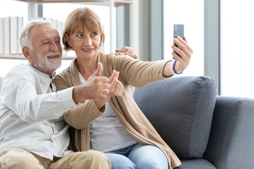 senior couple video call to someone or selfie from smartphone on sofa