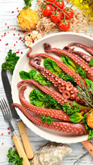 Baked octopus with spinach, lemon and parsley on a baking sheet. Top view. Flat lay.