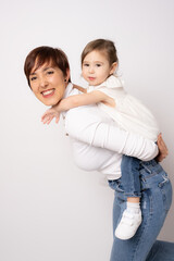 Photo of pretty young mommy hugging little daughter standing isolated over white background. Motherhood concept.