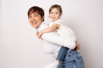 Photo of pretty young mommy hugging little daughter standing isolated over white background. Motherhood concept.