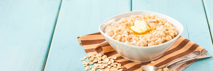 Porridge with oil in a bowl on a blue wooden background. Healthy breakfast. Selective focus. Copy space