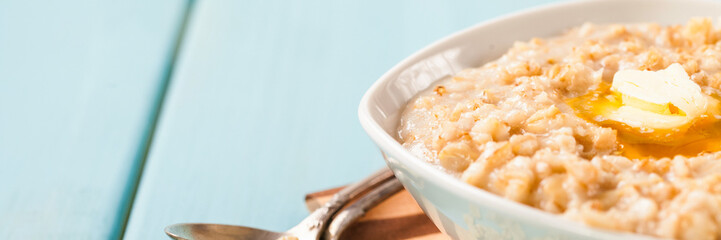 Porridge with oil in a bowl on a blue wooden background. Healthy breakfast. Selective focus. Copy space
