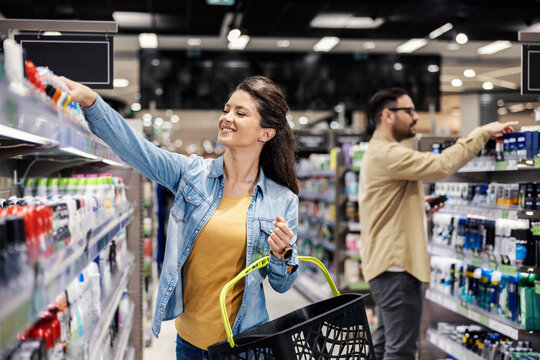 A happy woman choosing deodorant at supermarket.