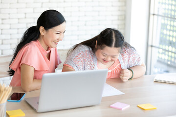 Obraz premium down syndrome teenage girl and her teacher using laptop computer and studying math on a table