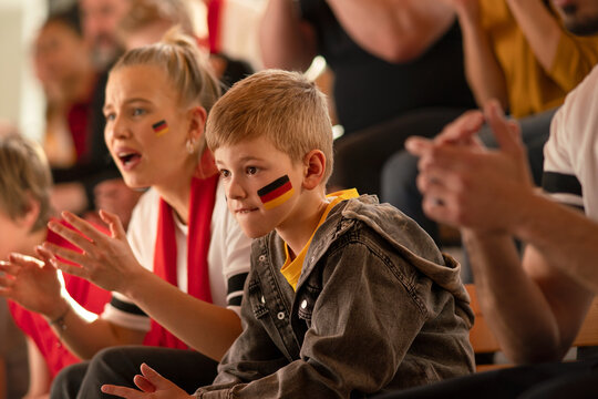Worried football fans supproting German national team in live soccer match at stadium.