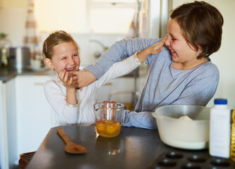 Adding some fun to the mix. Cropped shot of two young siblings having fun while baking together at home.