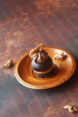 Chocolate Profiteroles (Cream Puffs) dipped in chocolate, garnished with whipped chocolate cream and walnuts, on a chocolate crunchy cookie base, on a dark brown background. 