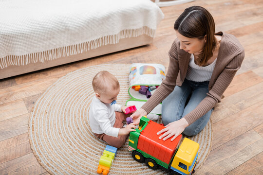 Overhead View Of Mother And Baby Son Playing With Building Blocks At Home.