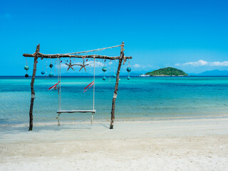 Scenic white sand beach tropical island with relax wooden swing and crystal clear turquoise sea water against blue sky in summer. Koh Mak Island, Trat, Thailand.