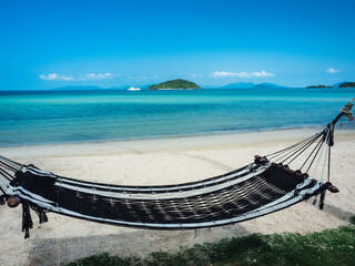Relax beach hammock on peaceful white sand beach tropical island with clear turquoise sea against blue sky with Koh Kham view at horizon. Koh Mak Island, Trat, Thailand.