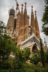 one of the facades of the Sagrada Familia framed by lush green trees
