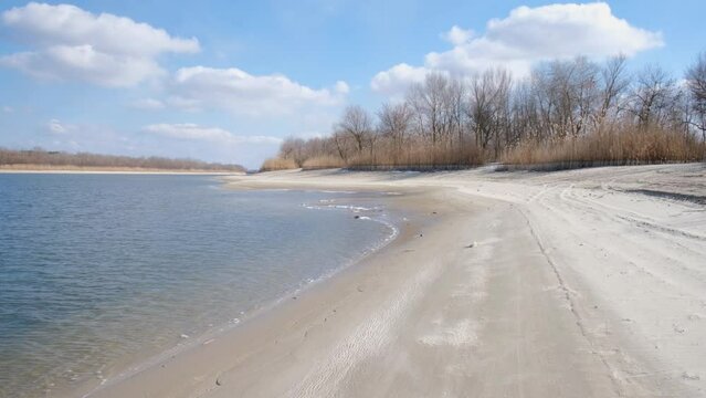 Winter landscape. An empty beach on the eve of spring. Waves on the water and cold sand. It's springtime, snow and ice are melting. The nature of the left bank of the Don River. Stanitsa Romanovskaya.
