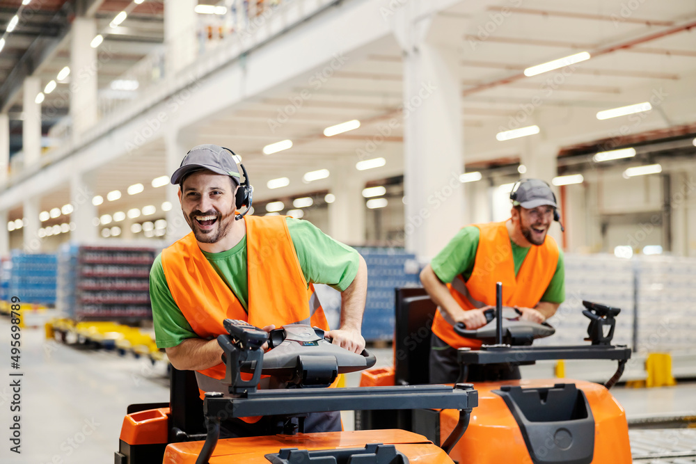 Canvas Prints Two warehouse workers having fun at work by driving forklifts.