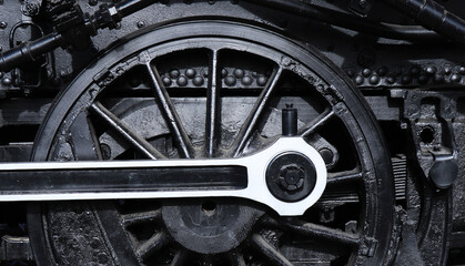 Grayscale shot of an old steam locomotive wheel
