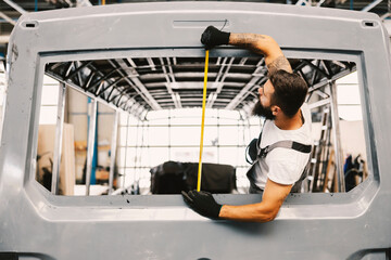 An auto-mechanic measuring bus window at workshop. © Dusan Petkovic