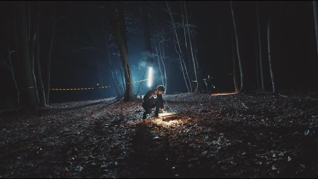 Detectives men searching and open case in woods at night with flashlight. Forest, equipment, searchlight, fog, criminal. Close up
