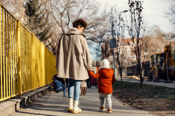 A babysitter or caregiver walking little boy to the kindergarten for the first day at school.