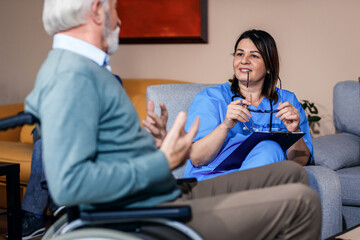 Female nurse talking to senior man at nursing home.