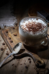 Cup of coffee with cream and chocolate on a wooden table