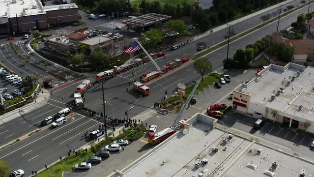 Aerial drone of police and fire trucks with huge American flag.