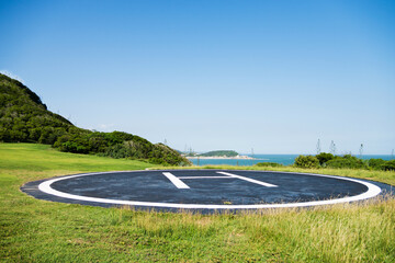 Empty helipad on island with blue sky background.