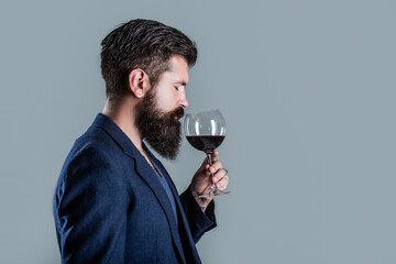 Man with a glass of red wine in his hands. Beard man, bearded, sommelier tasting red wine. Sommelier, degustator with glass of wine, winery, male winemaker - obrazy, fototapety, plakaty