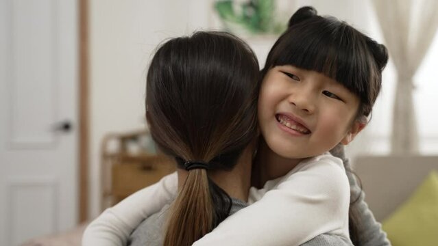 slow motion with selective focus of happy asian girl hugging her mom with a smiling face on mother's day in living room at home