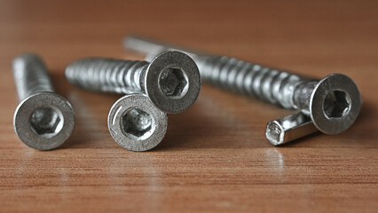 Fototapeta na wymiar hex bolt screw by hex wrench, the bolts lie on the table in the workshop. hex screws for furniture assembly. macro, close up.