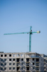 Large construction site cranes working on a building complex with clear blue sky.