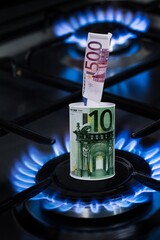 Concept of gas crisis and energy war. Banknote on burning a kitchen stove. Saving finance.