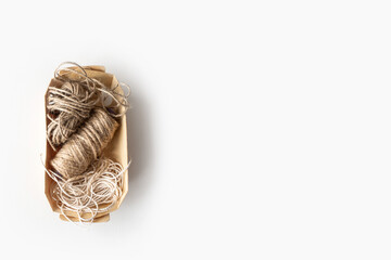 Jute twine coils in craft paper box isolated on beige background. Copy space