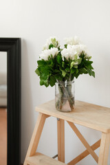 Bouquet of white flowers in a glass vase on a wooden shelf. Spring is in the city and in the soul. A festive bouquet. Morning surprise.