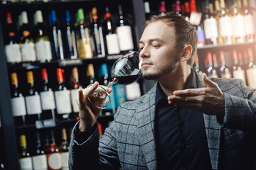 Portrait Sommelier holds glass with red wine in restaurant, tests aroma and color, dark background alcohol store