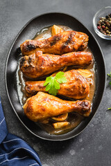 Honey mustard chicken legs in cast iron skillet on dark background. Top view, copy space.