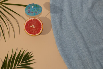 Top view of summer scene with a blue beach towel and palm leave and grape with parasol © Miki Mudric/Wirestock Creators