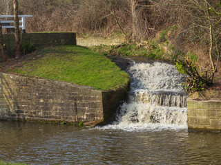 The bywater that protects the lock at Dowley Gap near Bingley in Yorkshire cascades down like a waterfall into the Leeds and Liverpool Canal