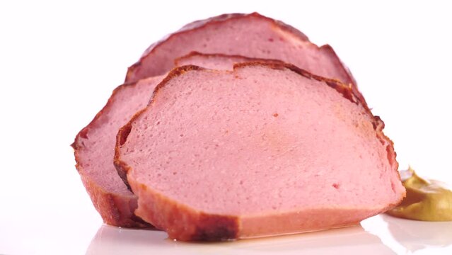 Fleischk&auml;se in Scheiben auf einem Drehteller freigestellt auf wei&szlig;em Hintergrund